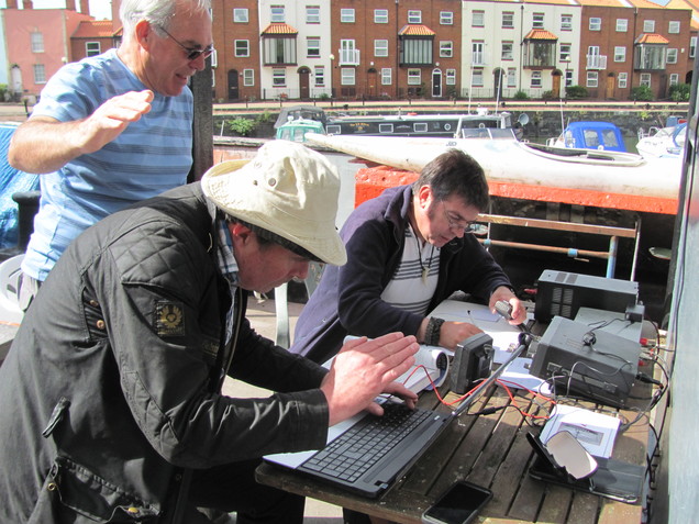 Henryk M0HTB operating GB0CCC with Julian M0JCE logging. Eddie M0LJT observes and shades the laptop screen from the sun